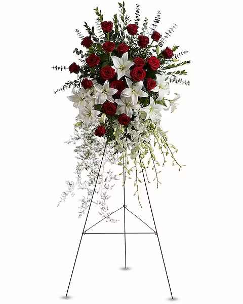 Standing floral spray with red roses and white lilies on an easel