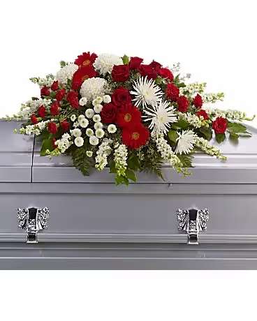 Red and white floral casket spray on a gray casket