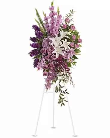 Tall purple floral standing spray on an easel with white lilies