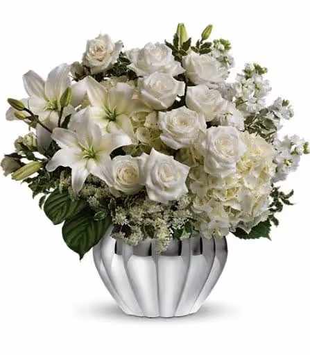 White roses and lilies arranged in a silver vase