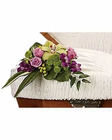 Purple and green floral spray on a white casket