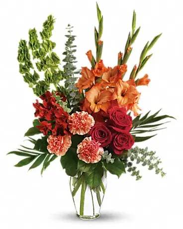 Tall bouquet of orange and red flowers in a clear glass vase