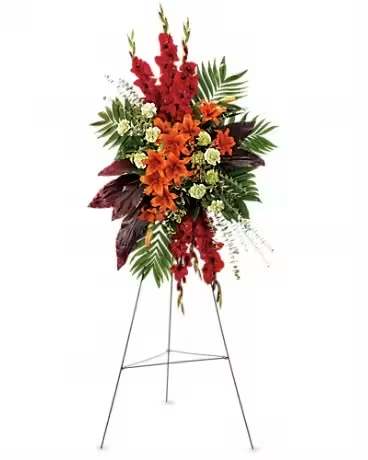 Standing floral spray with red and orange flowers on a metal easel