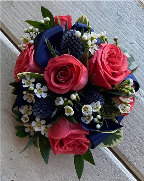 Bouquet of pink roses with white filler flowers and dark blue ribbon