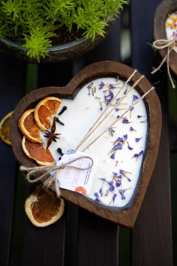 Heart-shaped wooden candle with dried orange slices and purple petals