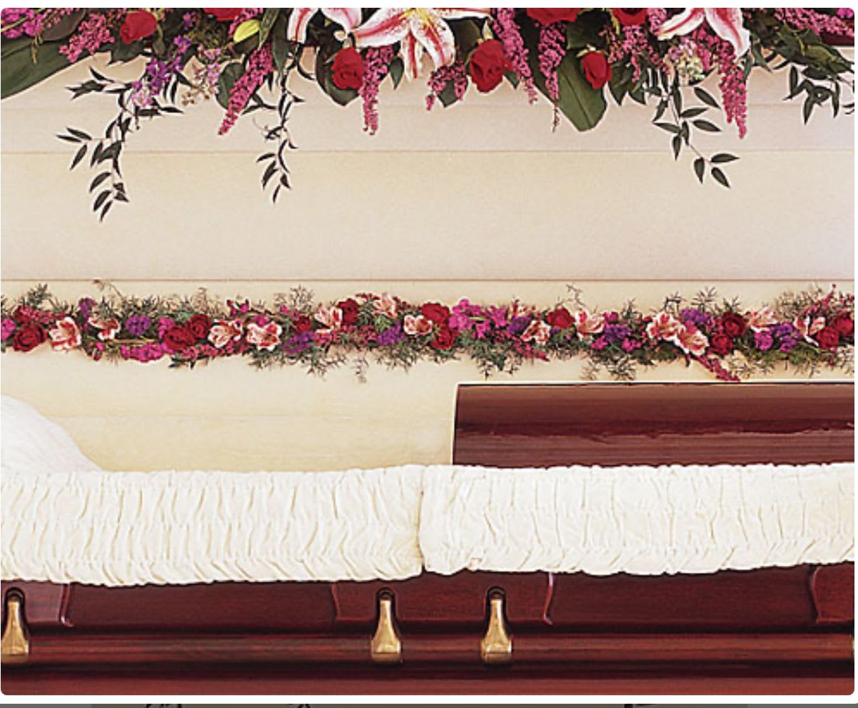 Casket with white drape and red floral sprays