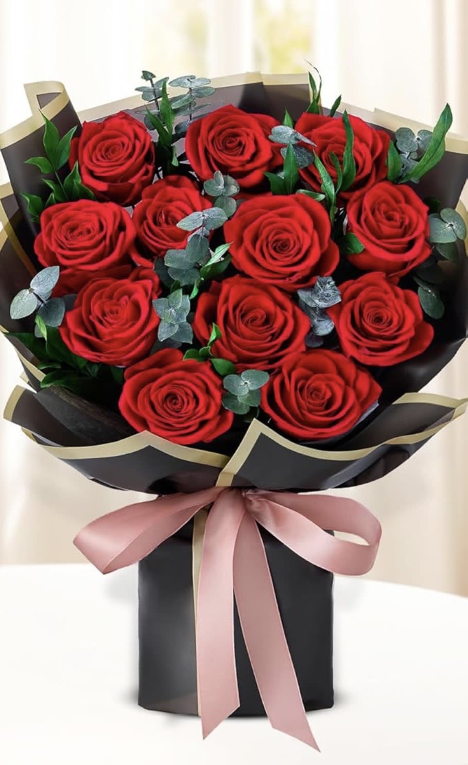 Bouquet of red roses wrapped in black paper with a pink ribbon