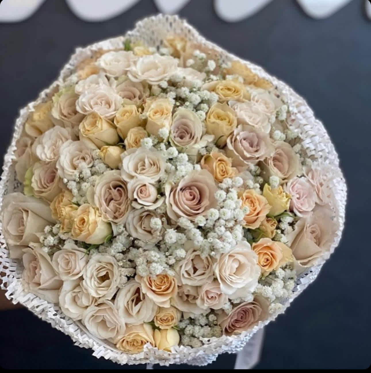 Round bouquet of cream and blush roses with white filler flowers