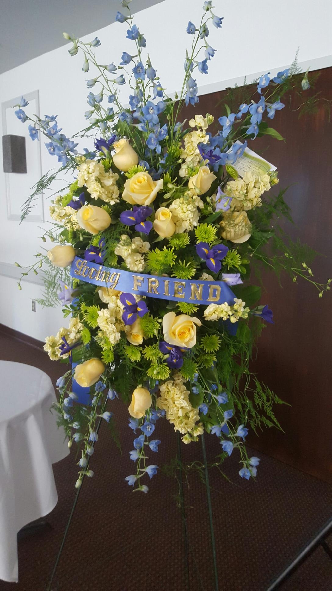 Tall floral standing spray with yellow roses and blue flowers