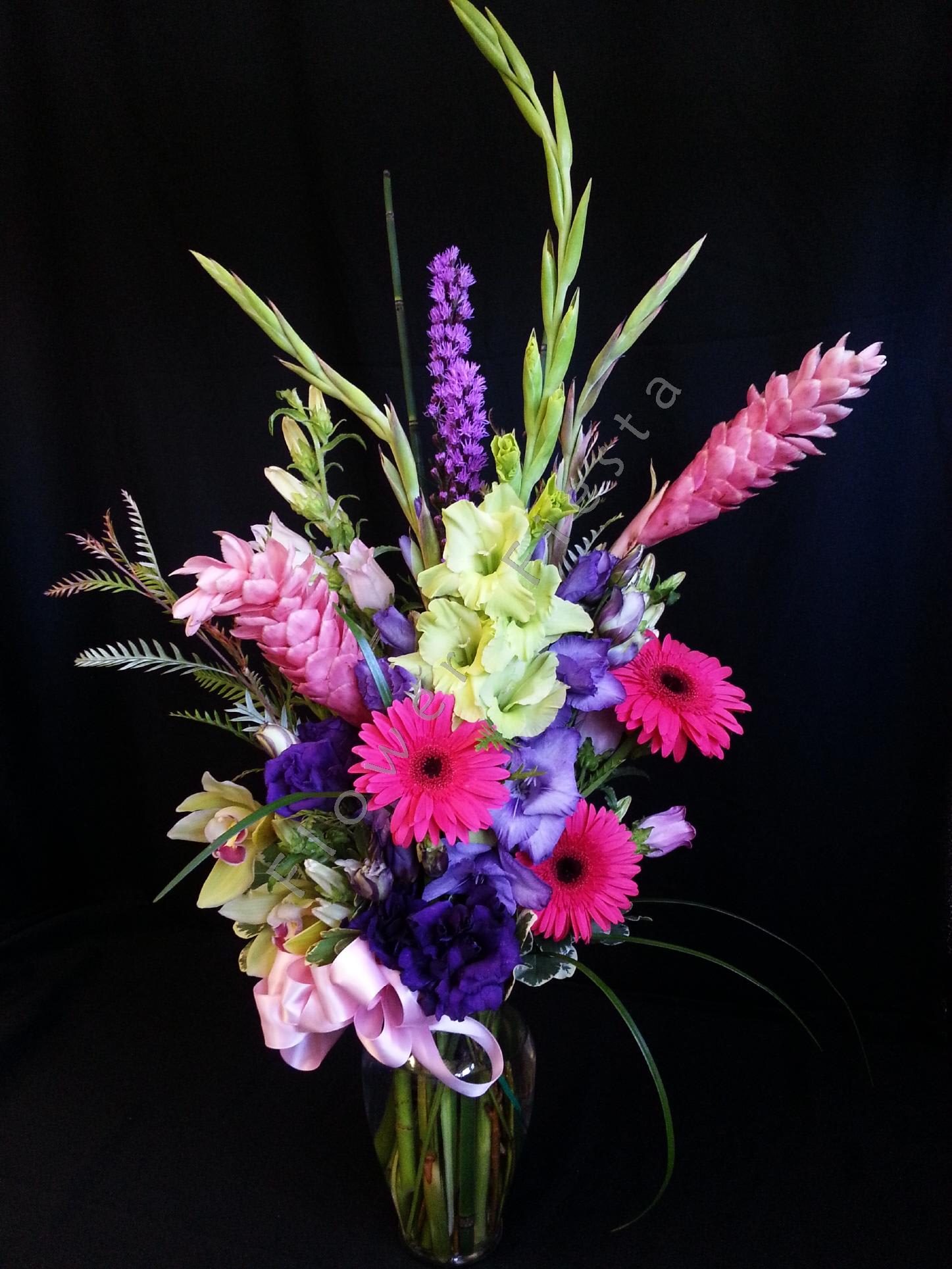 Tall mixed bouquet in a glass vase with pink, purple, and green blooms