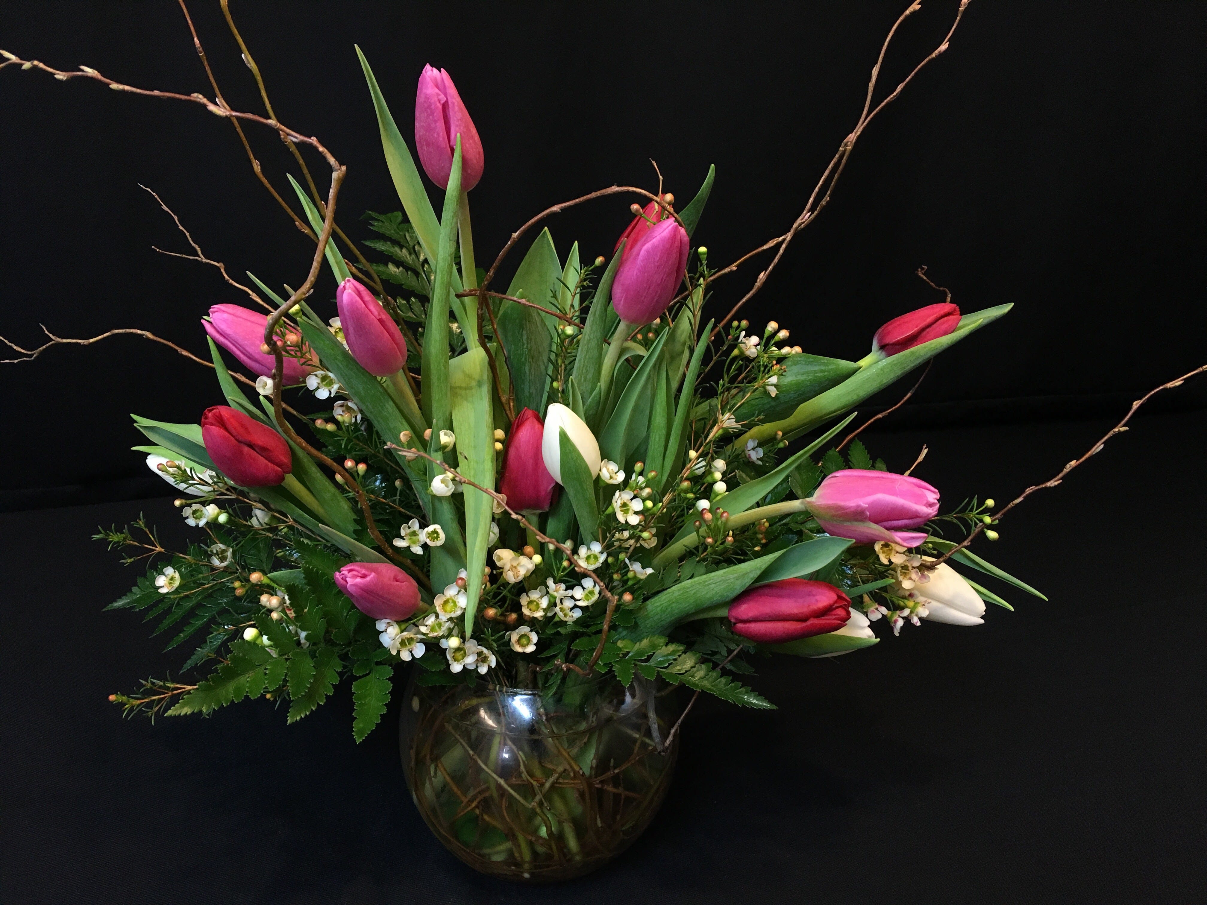 Tulip willow bowl for Valentine's Day - An assortment of 15 locally grown spring tulips and filler flower plus whimsical willow branches. Valentine color scheme and filler will vary. Elegant creation. May not be available when local temperatures exceed 90 degrees or when there is excessive rain. Exceptional in winter