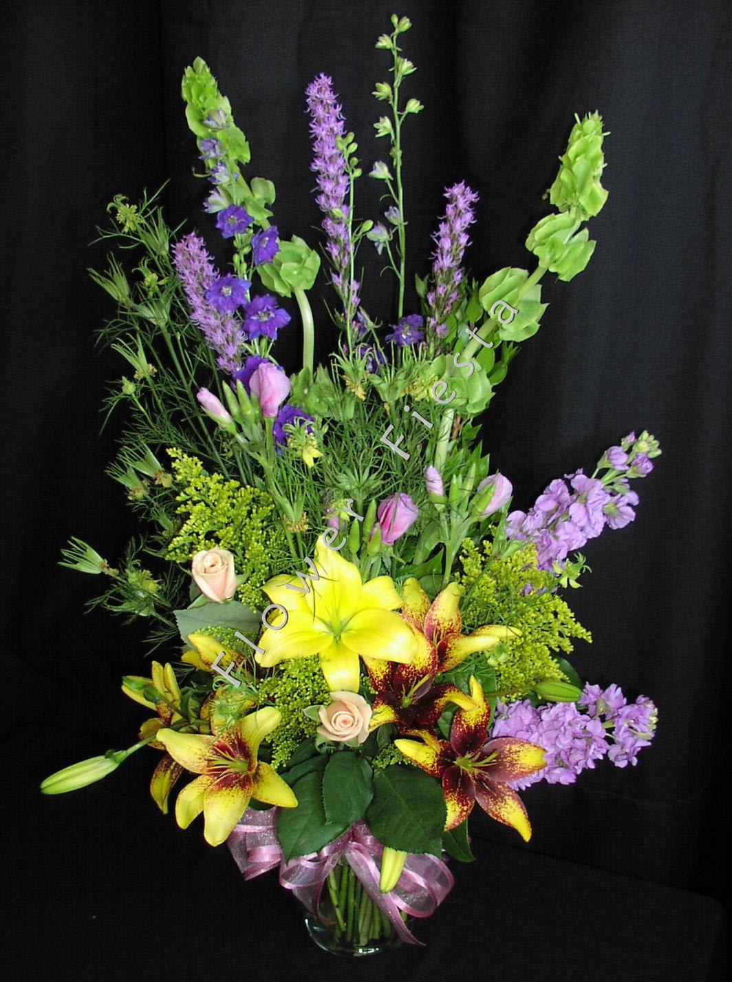 Mother's day botanical mix - Lovely mix of seasonal flowers* arranged in a natural botanical style with soft and delicate filler flowers.  Shown here are lilies, transformer, bells of Ireland, liatris, larkspur, solidago, godetia and Sahara roses.  Perfect Mother's day bouquet for the discerning mother