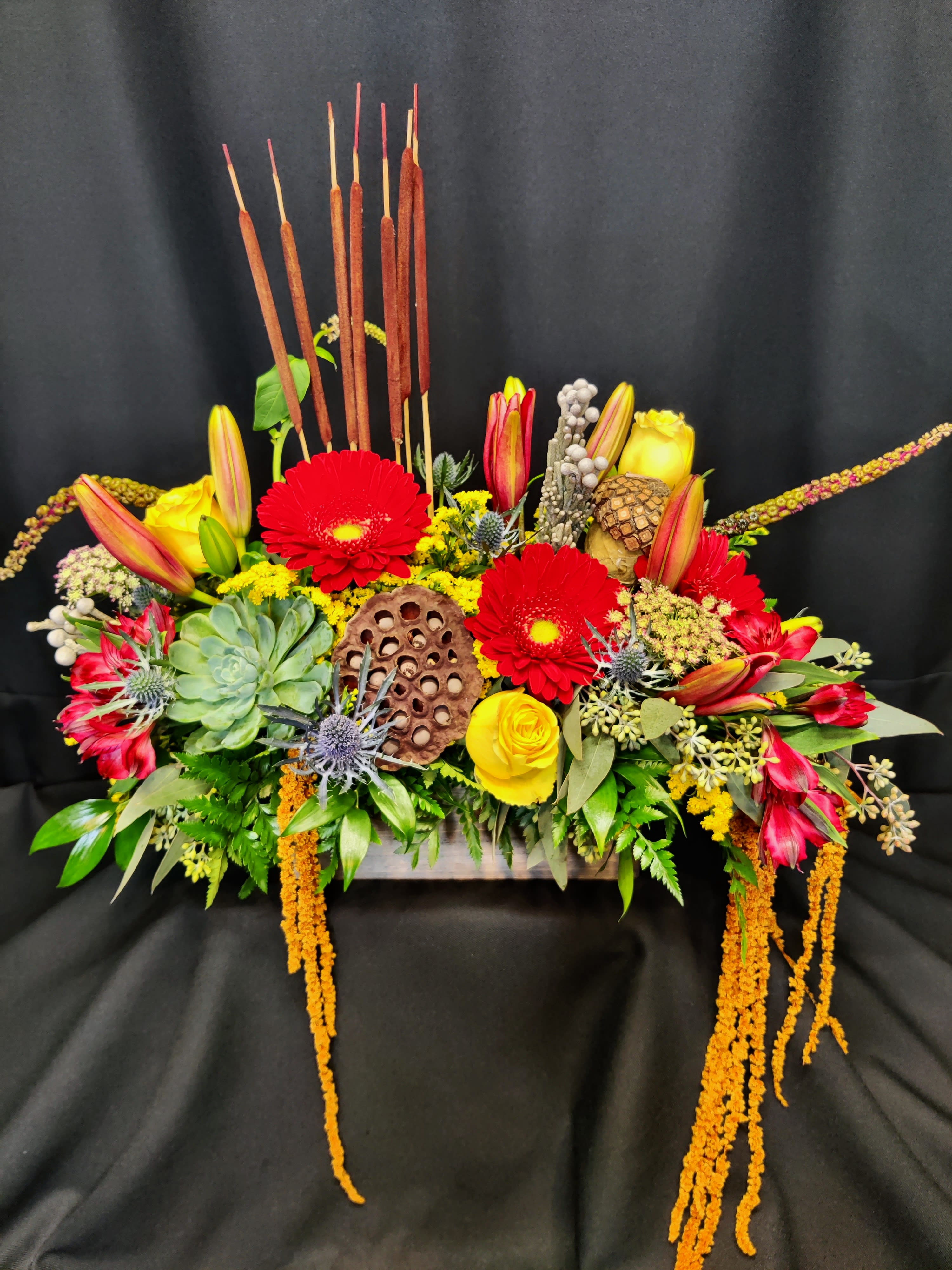 Fall Box Centerpiece with Cat Tails, Deluxe - Rustic box of fall flowers, some roses and lots of texture. Colors and items will vary. Cattails up top make this a super fun arrangement that makes any tabletop festive.