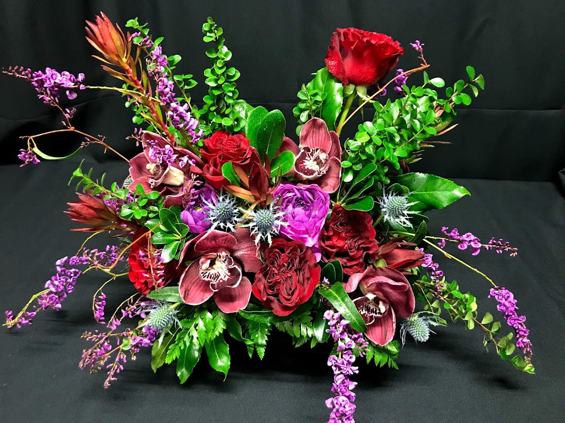 Red roses and purple orchids in a low floral arrangement