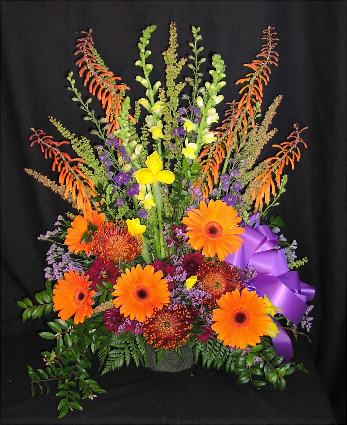 Brightest Memorial Mache Basket Spray - Seasonal selection of your brightest boldest color flowers. Assortment and colors will vary. If you'd like to select colors or flowers, be sure you have ordered a full week ahead.  This is well contained in a simple paper mache container and floral foam so that no water will splash around if transported after the service.
