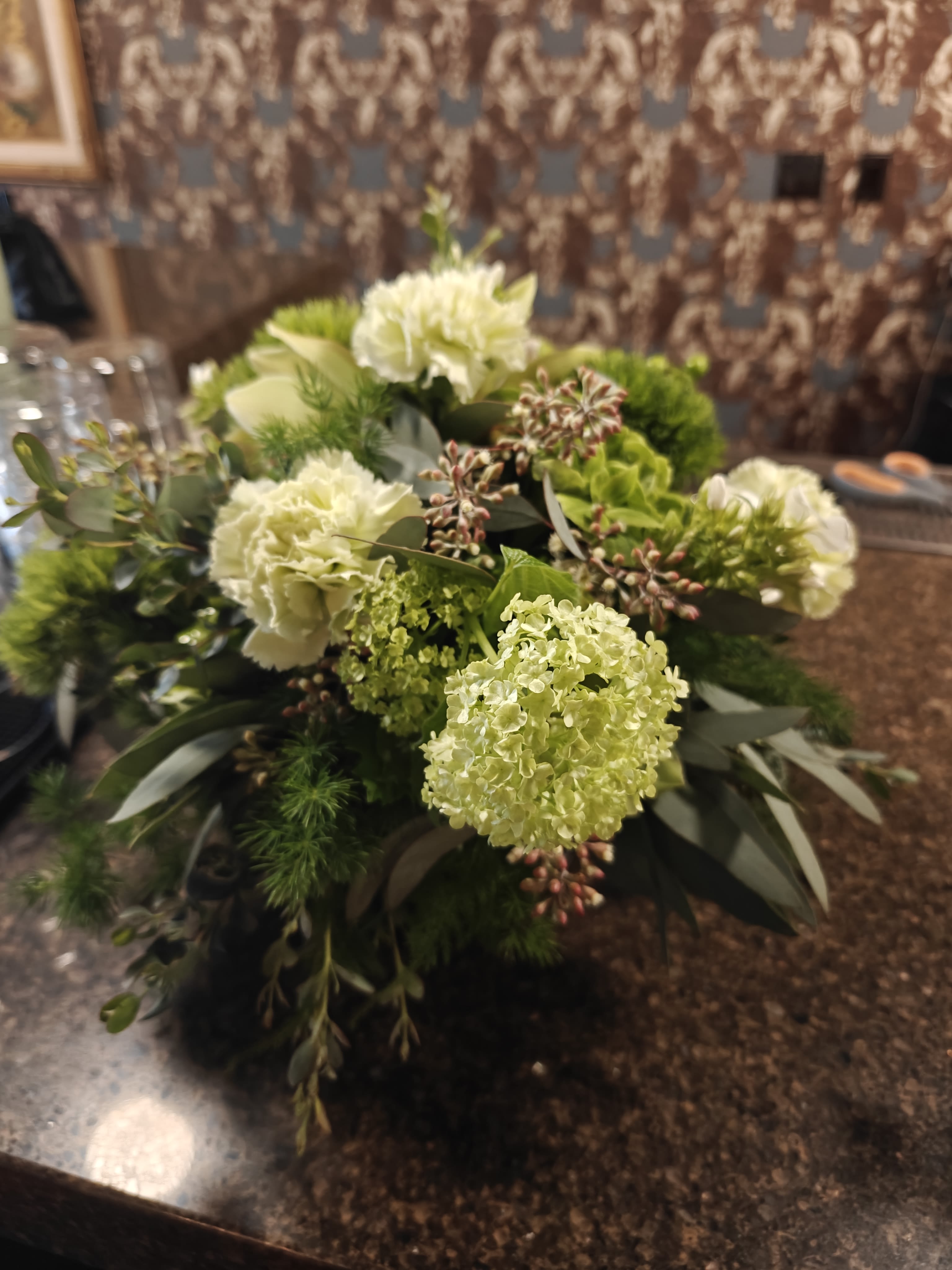 All Green Centerpiece  - Shades of green flowers and foliage in a round centerpiece for the dining or cocktail table. Great event centerpiece. The standard size shown is approximately 5-7" wide. 