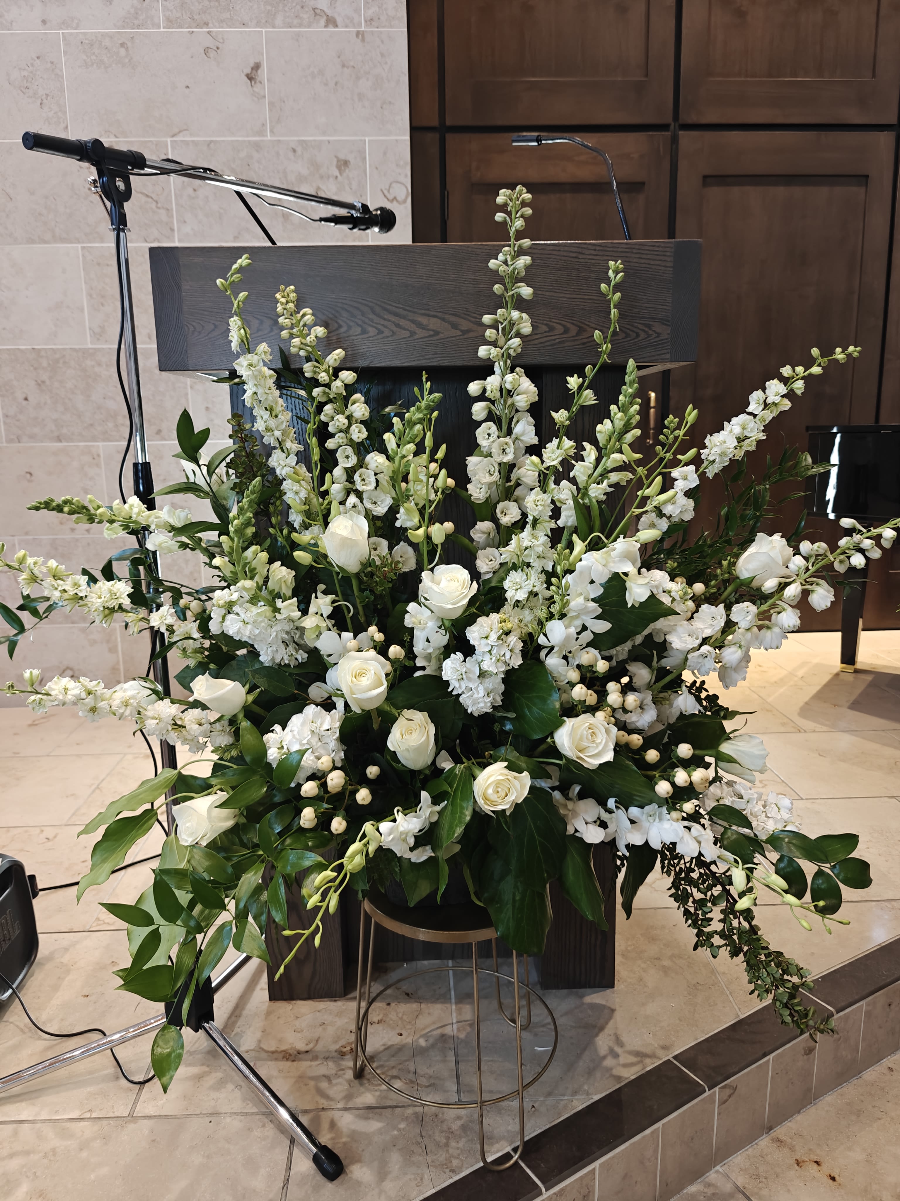 All white Spray of flowers - Pure white flowers and lush foliage in a paper mache pot. This sits sturdily at a memorial service, even if displayed on the lawn at burial. Flowers fan out and can be appreciated in a tall and wide display. Flowers will vary.  Customize this with specific flowers or another color if you like but be sure to place your order at least a week ahead or confirm that we are able to fulfill special requests. 