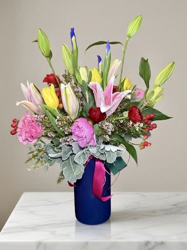Colorful bouquet of lilies, tulips, and carnations in a blue vase