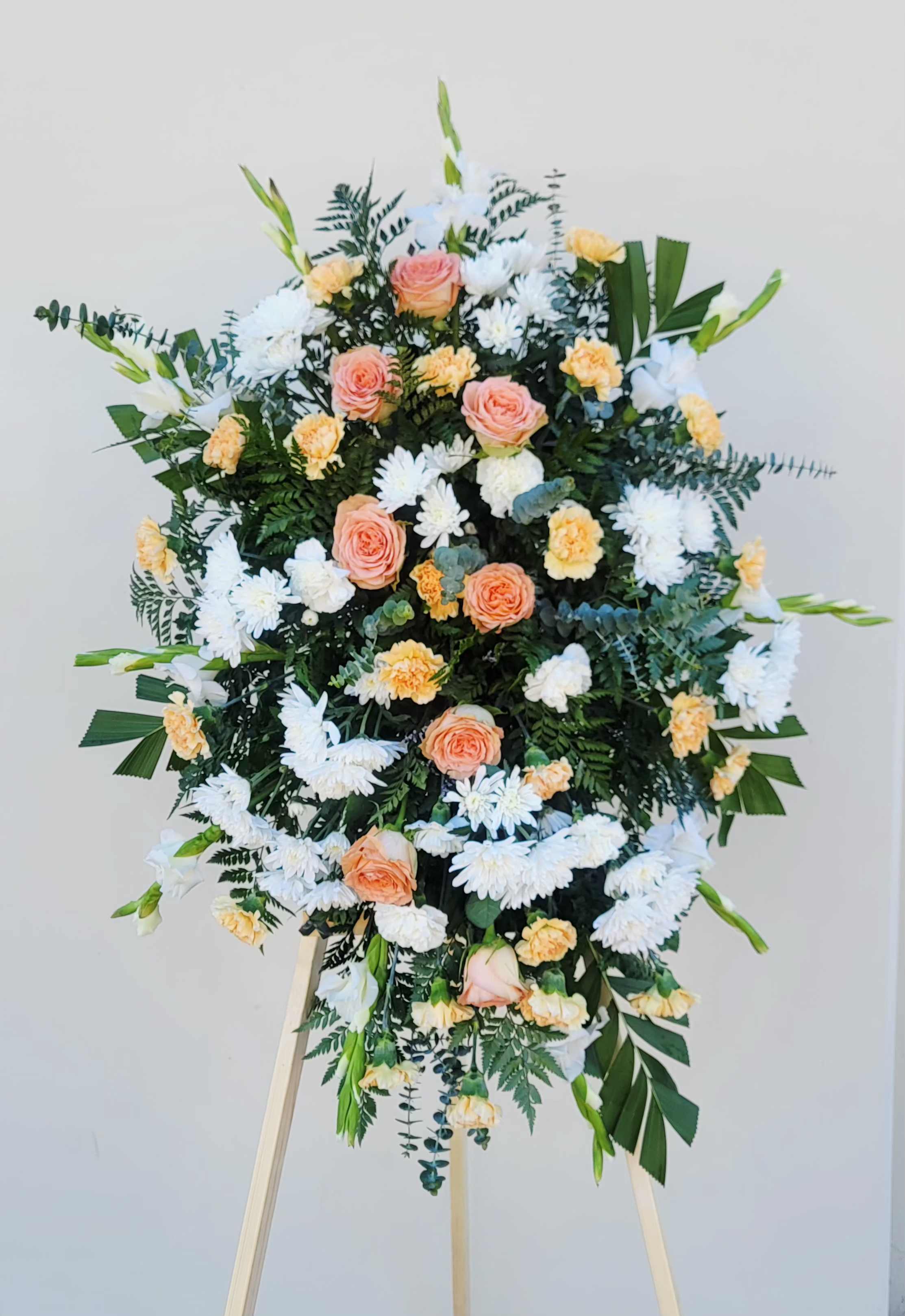 Standing floral spray with peach roses, white daisies, and yellow carnations