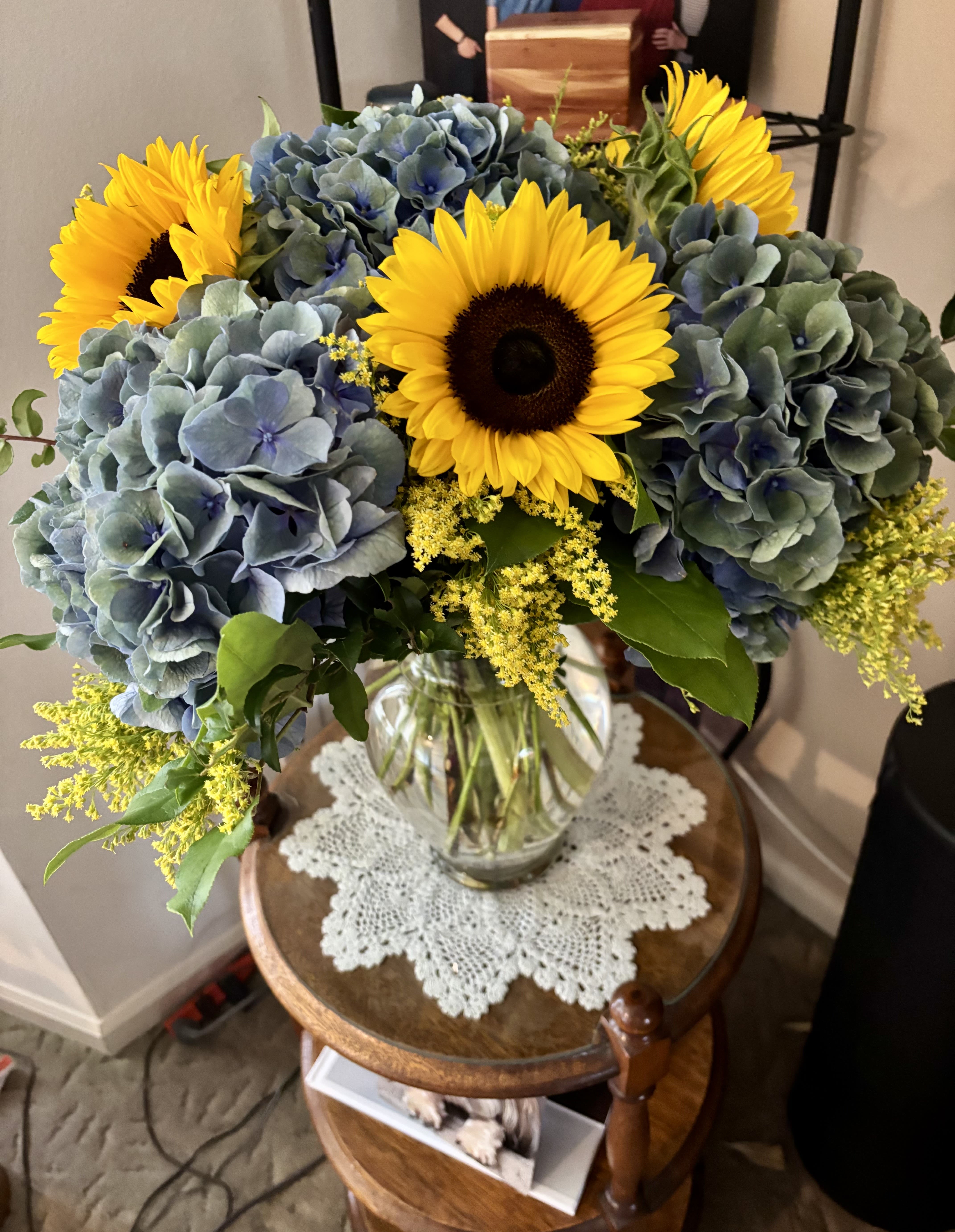 Bouquet of sunflowers and blue hydrangeas in a clear glass vase
