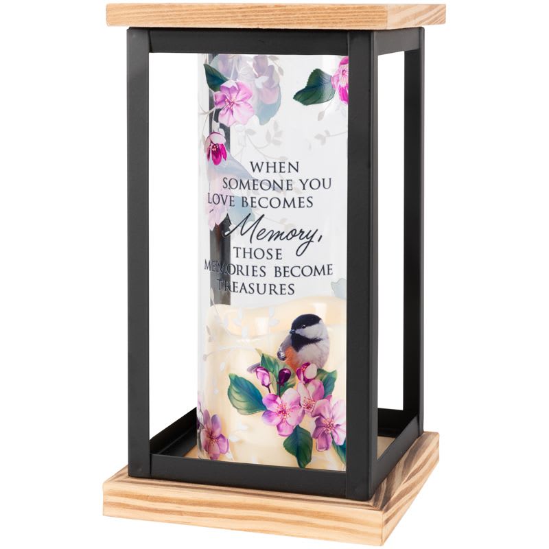 "Memories Become Treasures" Framed Cylinder Lantern - This tabletop lantern is comprised of a flameless LED candle inside a glass cylinder that is framed with wood and metal. The cylinder is adorned with full color artwork.  Lantern reads: "When someone you love becomes a memory, those memories become treasures."  W: 4.75" H: 8.5" D: 4.75"