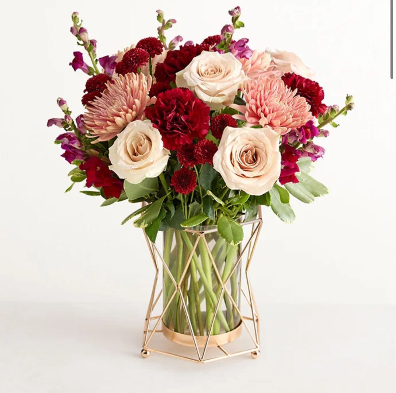 Bouquet of cream roses, pink mums, and red carnations in a glass vase