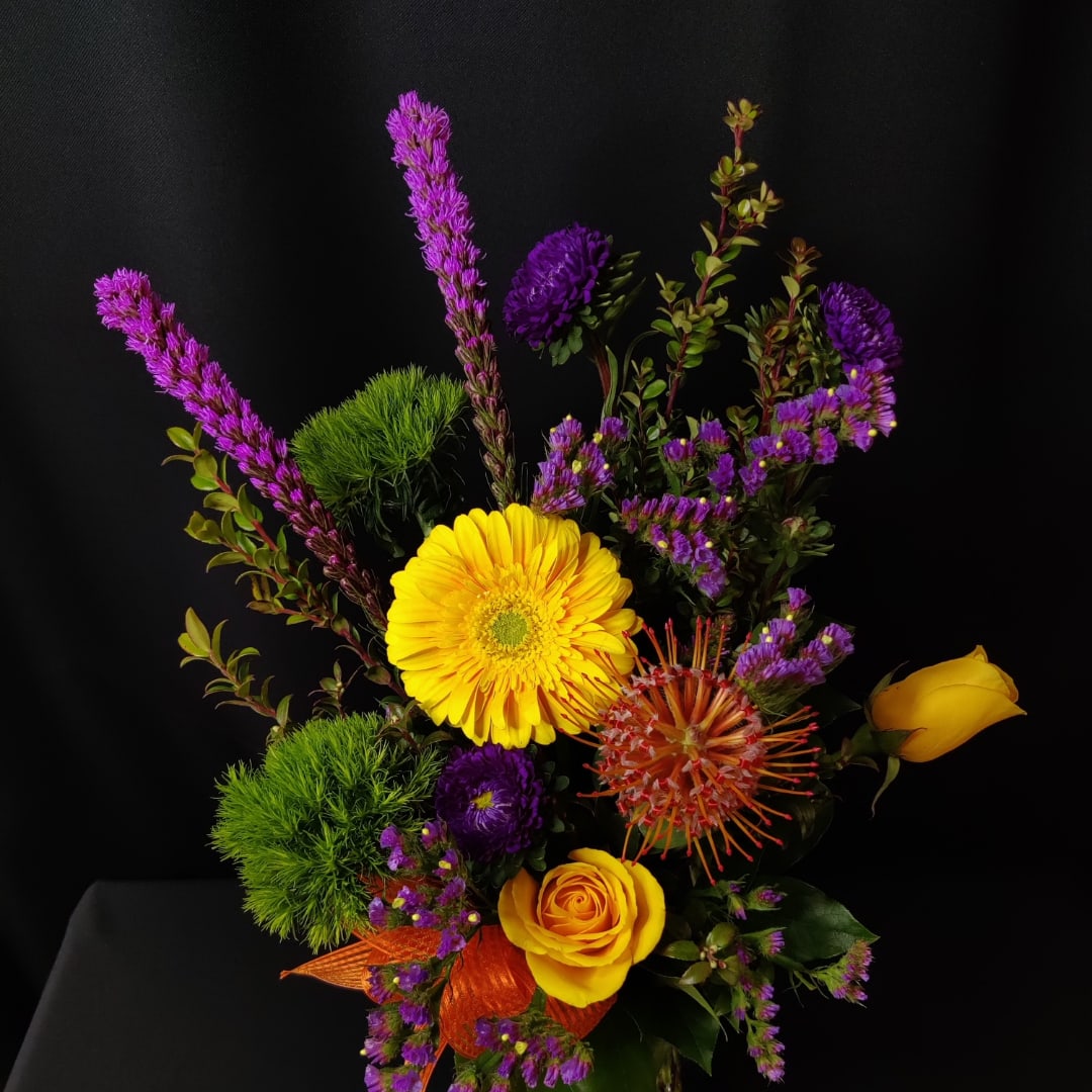 Yellow gerbera and roses with purple accents in a bouquet