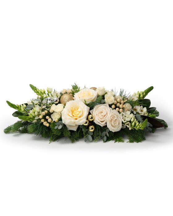 Low centerpiece of white roses and other flowers with evergreens and gold ornaments