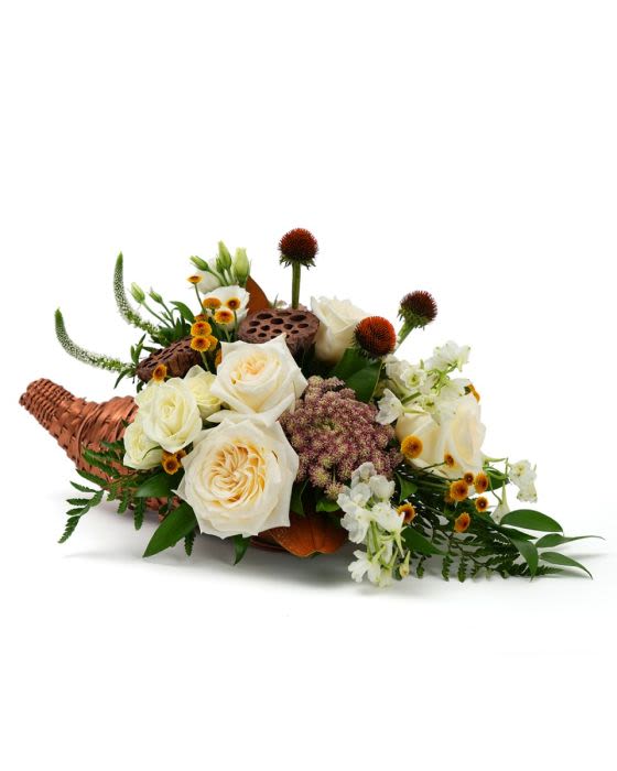 Cornucopia centerpiece with cream roses, white blossoms, and small yellow flowers in a woven horn basket.