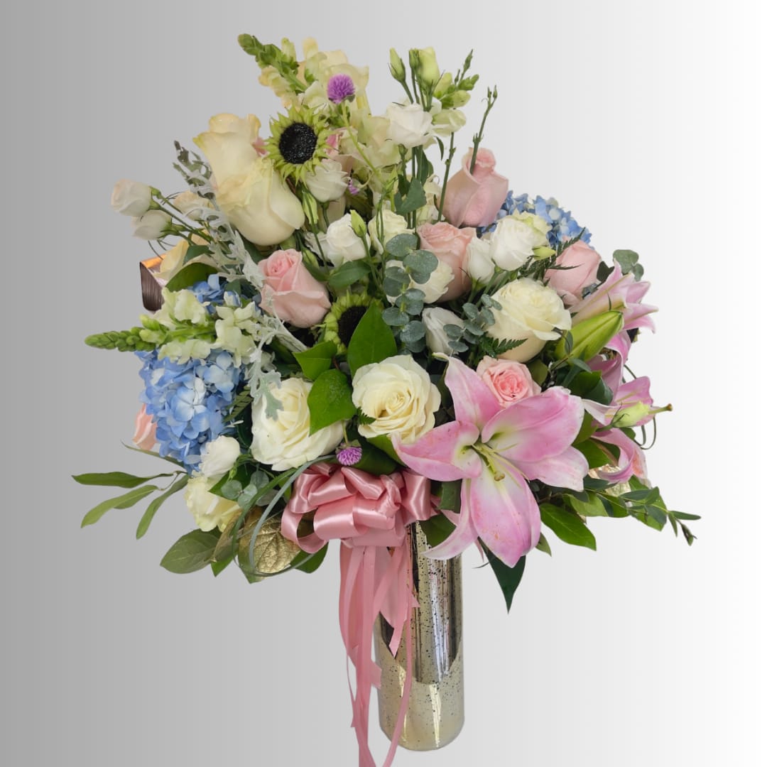 Mixed bouquet of roses, lilies, hydrangeas, and sunflowers in a tall vase