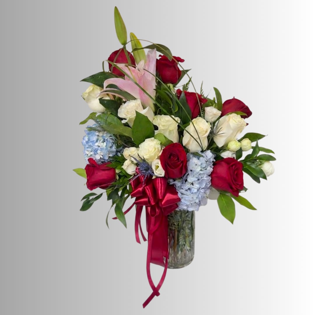 Mixed bouquet of red and white roses with pink lilies in a glass vase