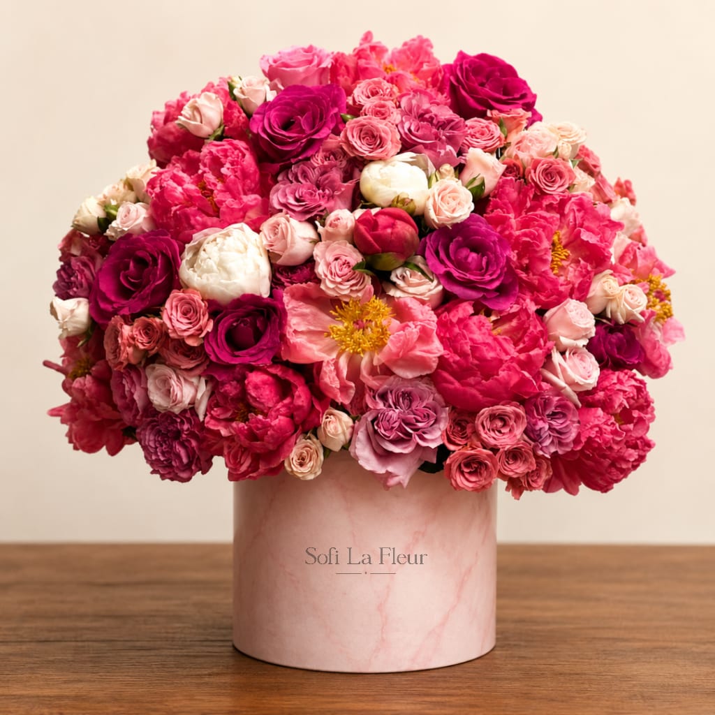 Pink and magenta rose bouquet in a blush cylindrical vase