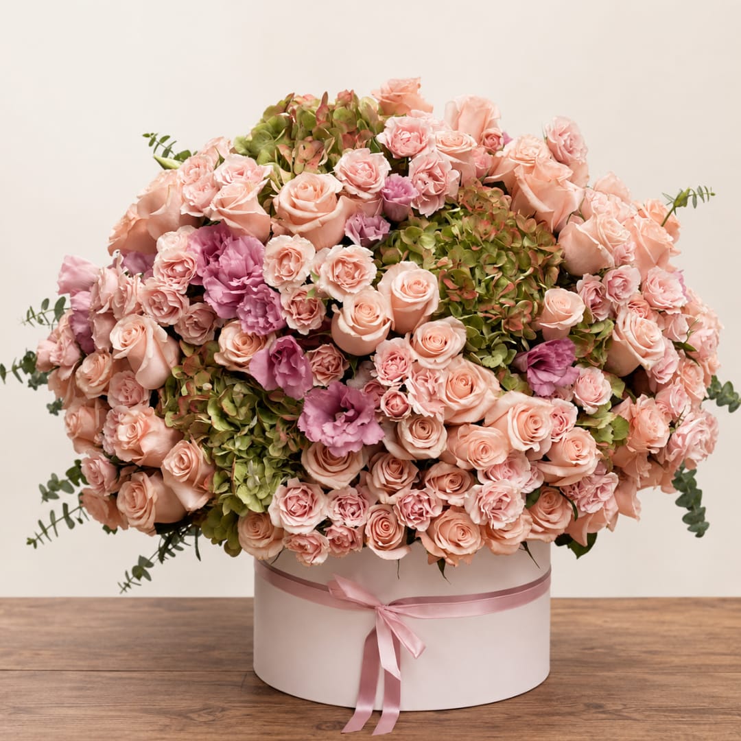Large pink and peach rose arrangement in a round box with ribbon