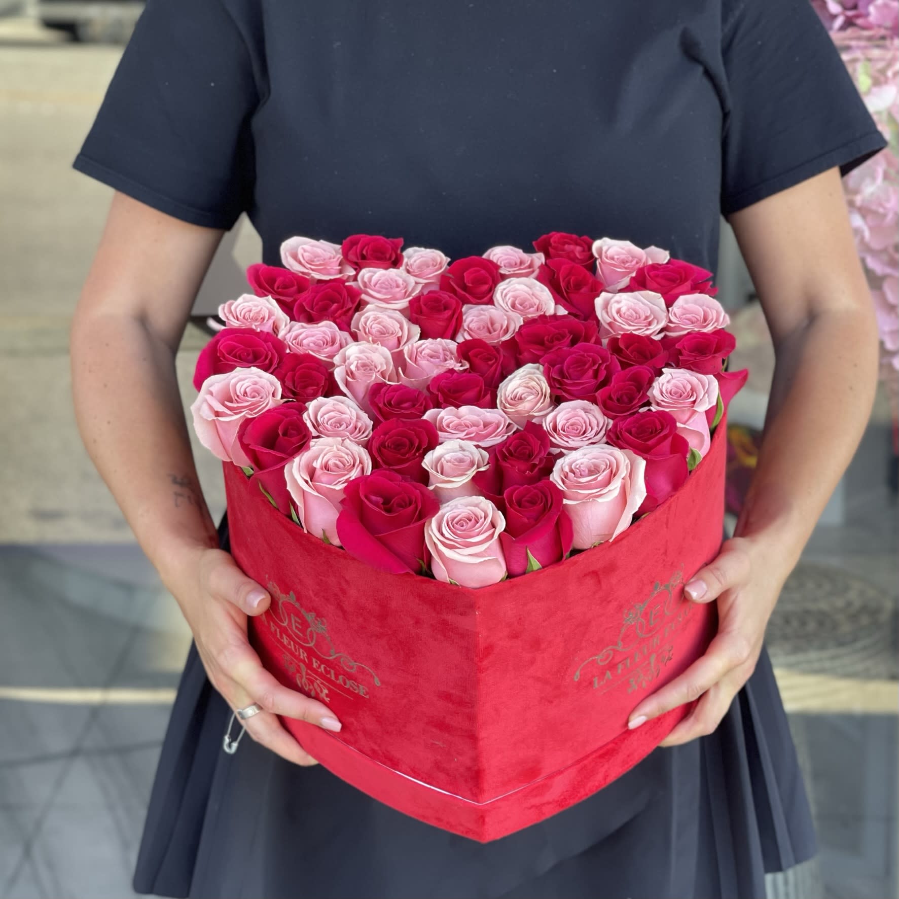 Heart-shaped box of pink and red roses held by a person