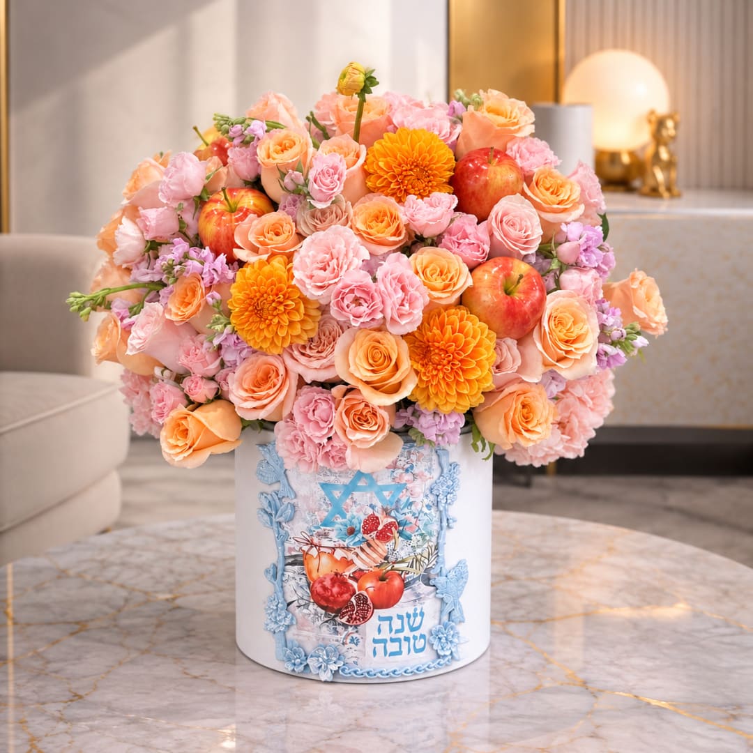 Pink and peach flower arrangement in a white box with apples