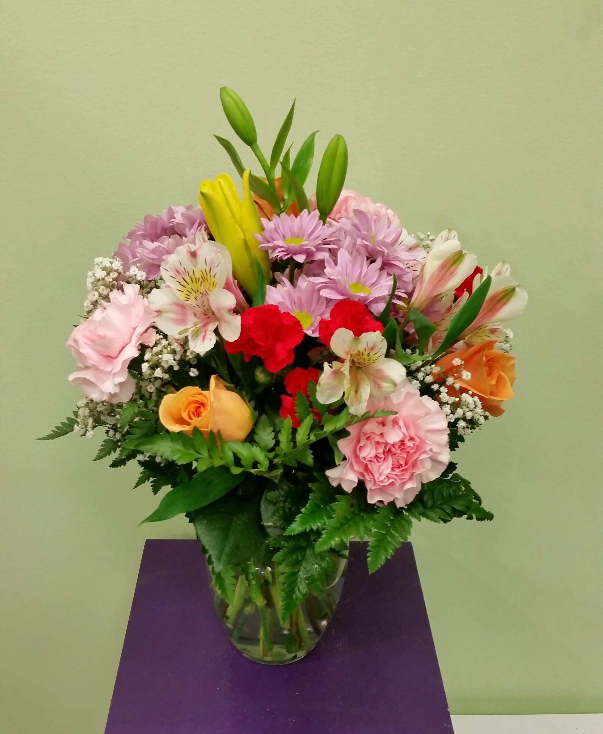 Mixed bouquet of pink, red, yellow, and orange flowers in a glass vase