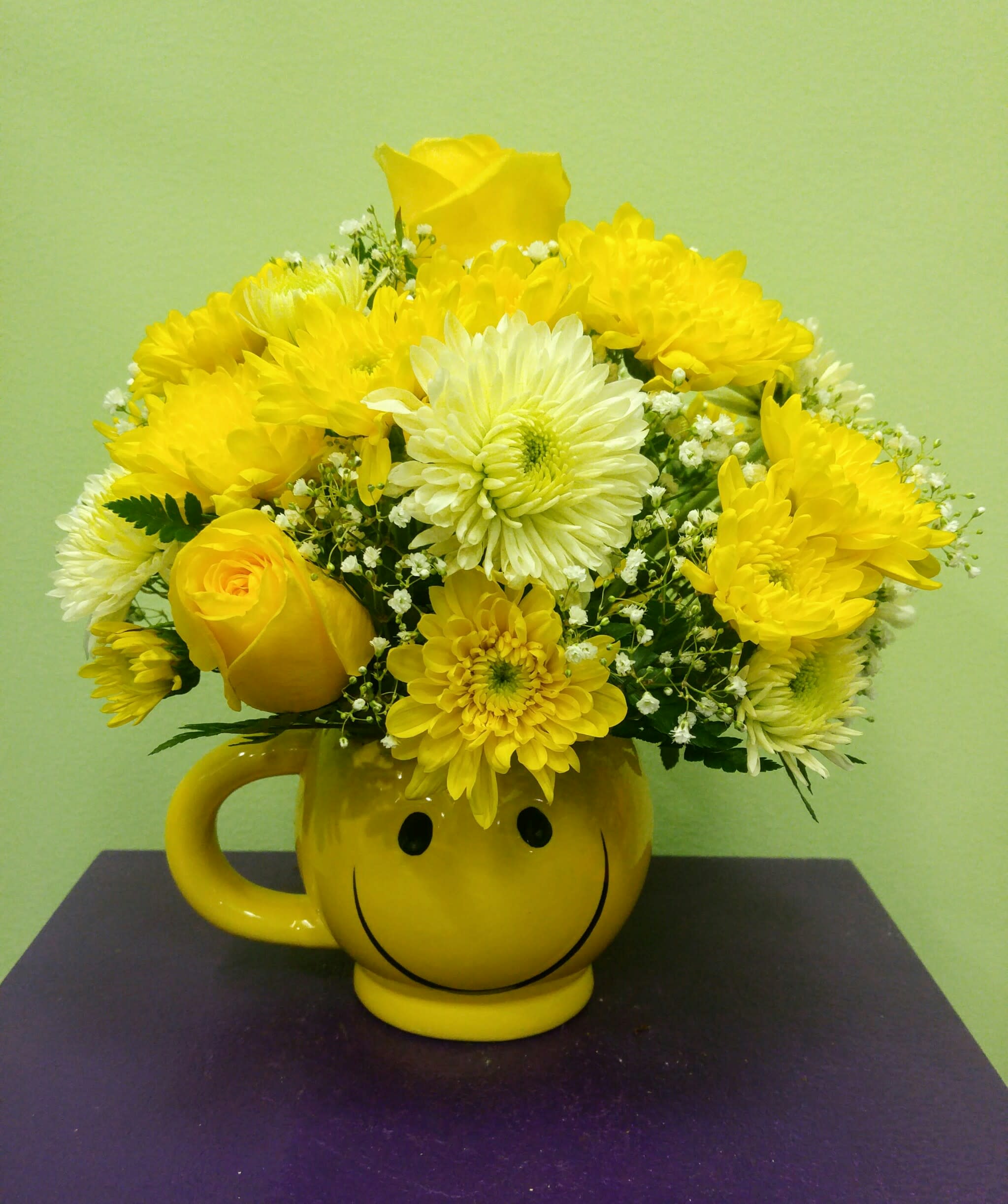 Yellow flower bouquet in a smiley-face mug vase