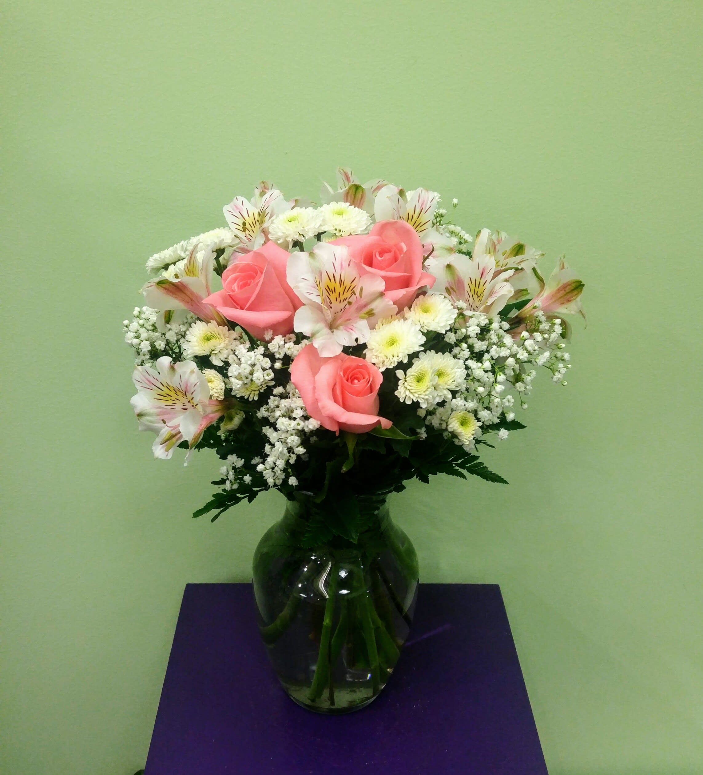 Pink roses and white flowers arranged in a glass vase