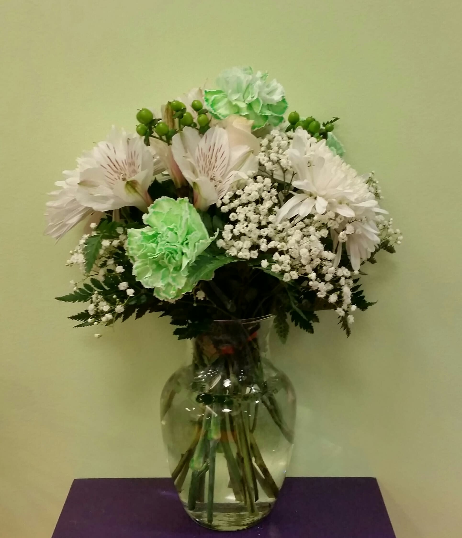 White and green bouquet in a clear glass vase