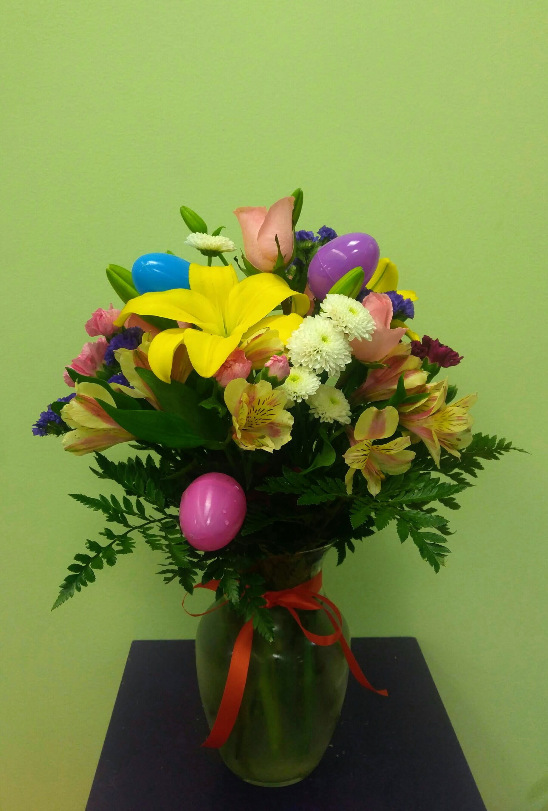 Colorful bouquet in a green vase with decorative plastic eggs