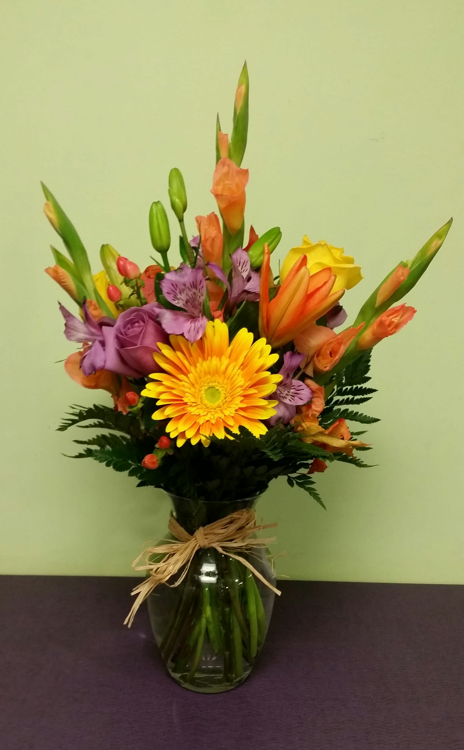 Mixed bouquet in a glass vase with yellow, orange, and purple flowers
