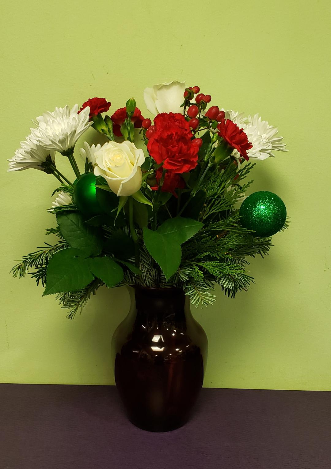 Red and white flowers arranged in a dark vase with green ornaments