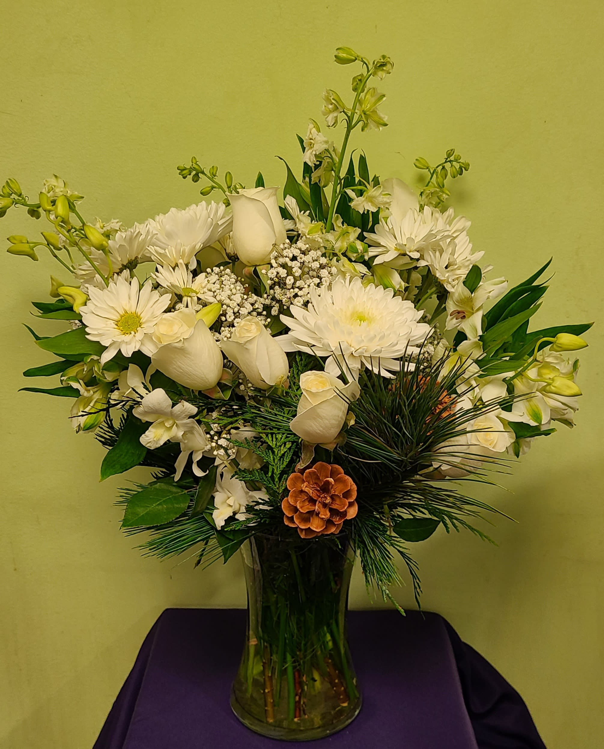 White flowers arranged in a clear glass vase with greenery