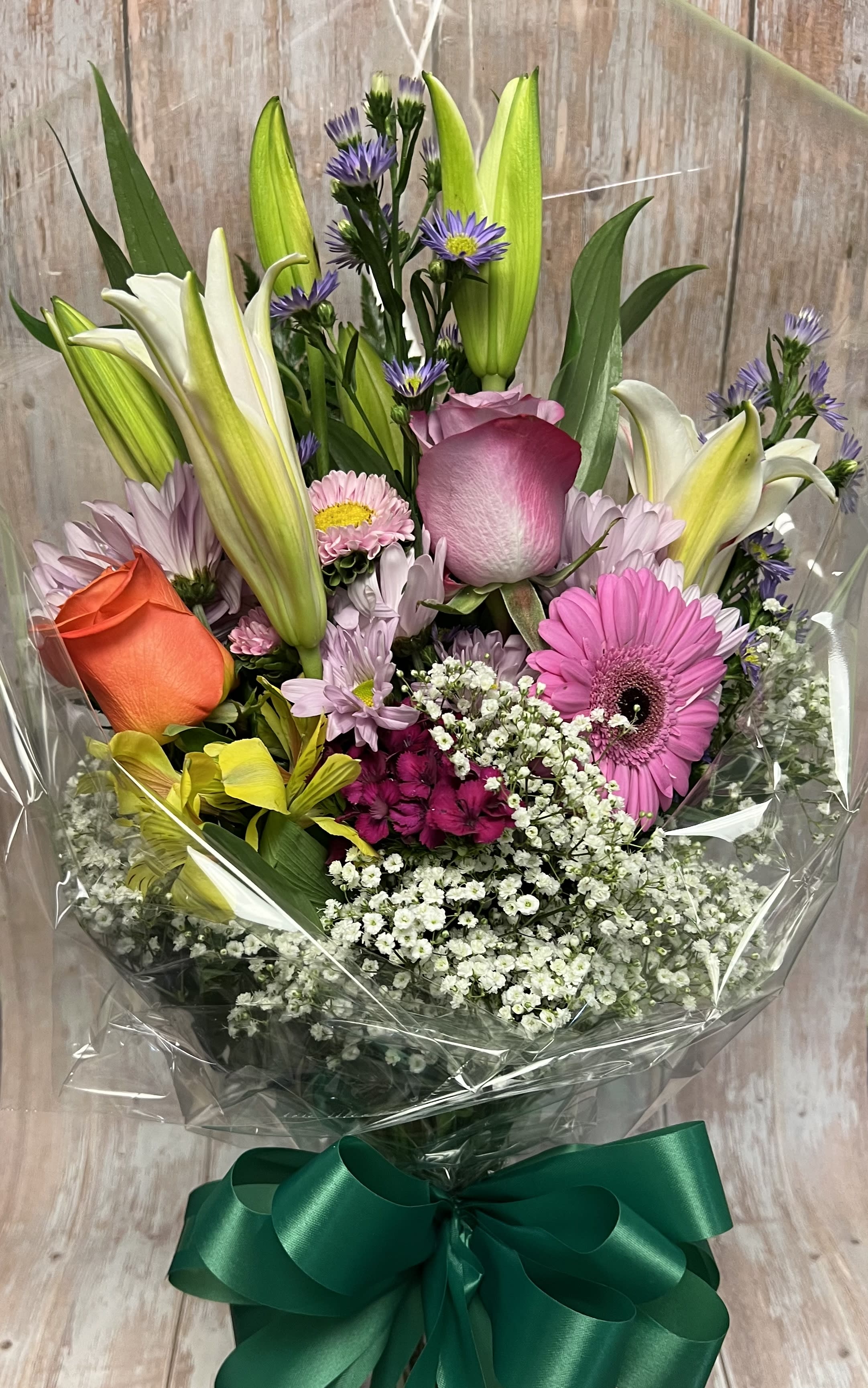 Mixed bouquet with lilies, roses, gerbera daisies, and purple filler flowers