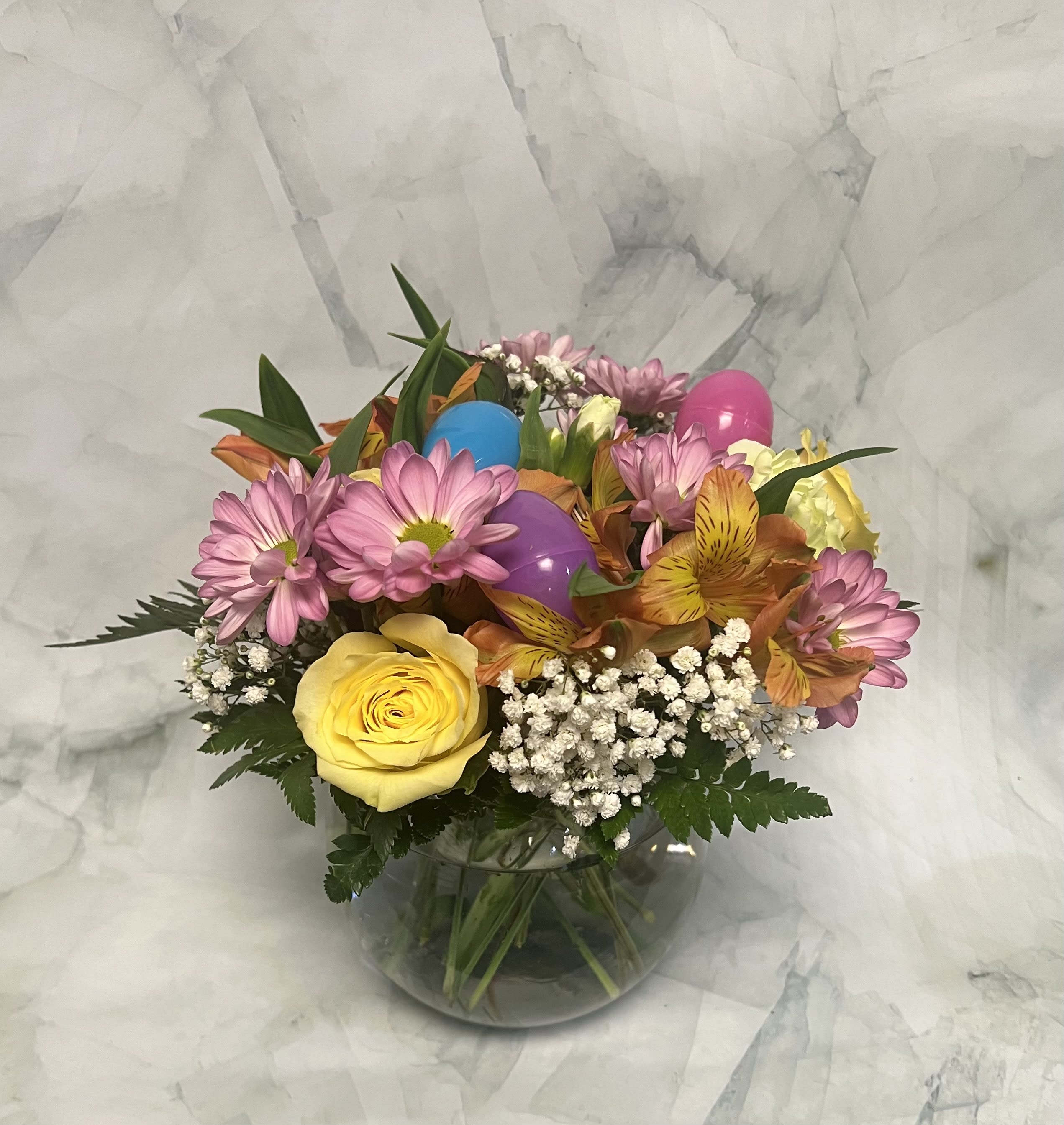 Mixed bouquet of pink daisies, yellow rose, and alstroemeria in a glass vase