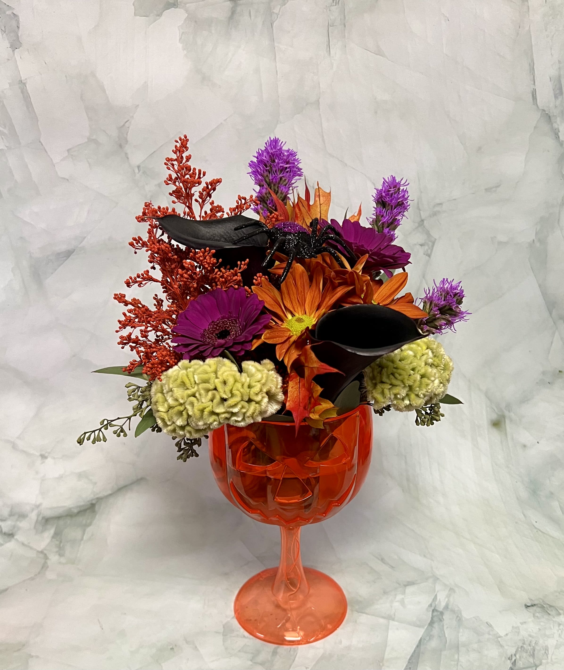 Halloween bouquet in an orange goblet vase with black spider and orange flowers