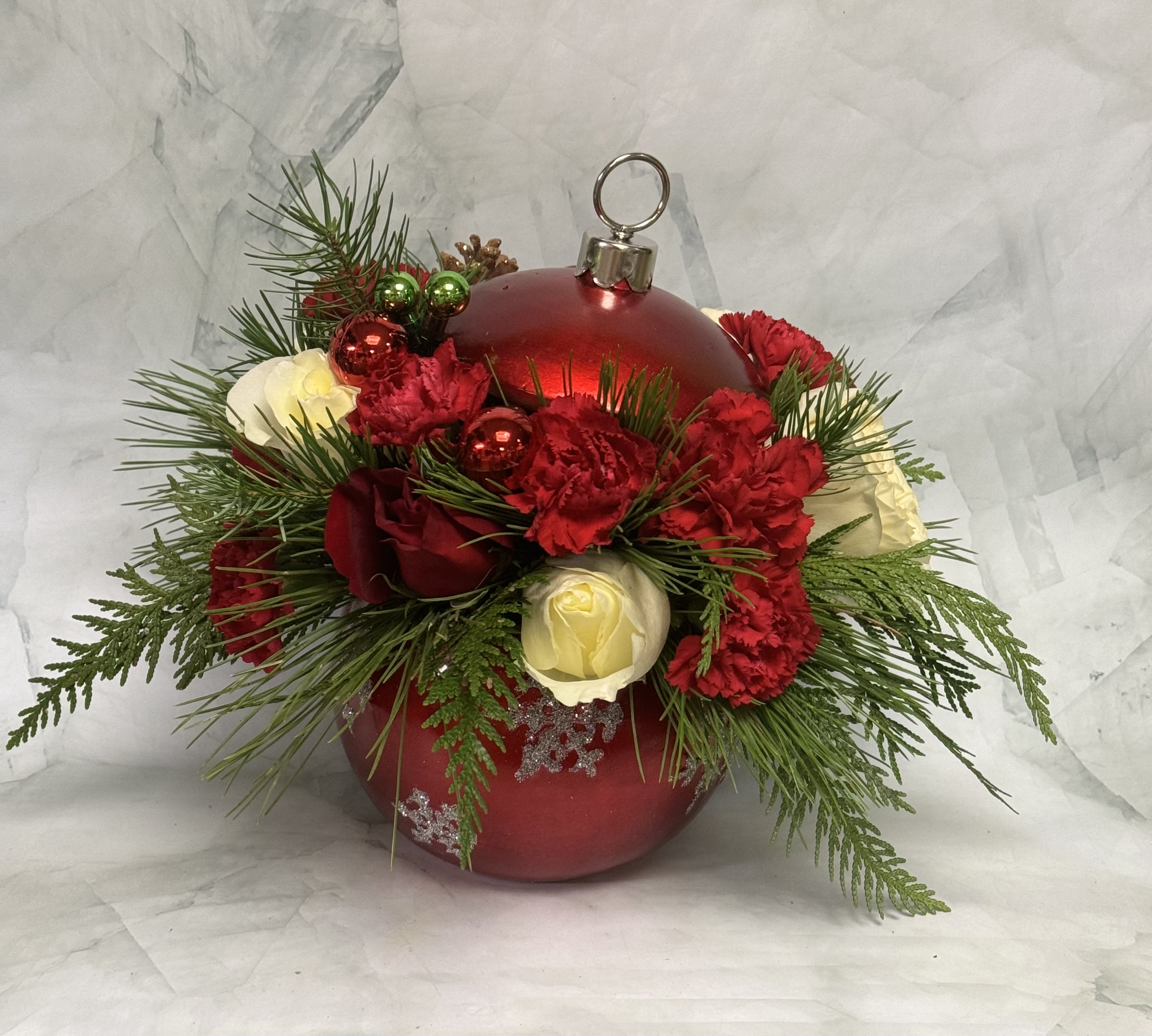 Red ornament with red and white flowers and evergreen sprigs