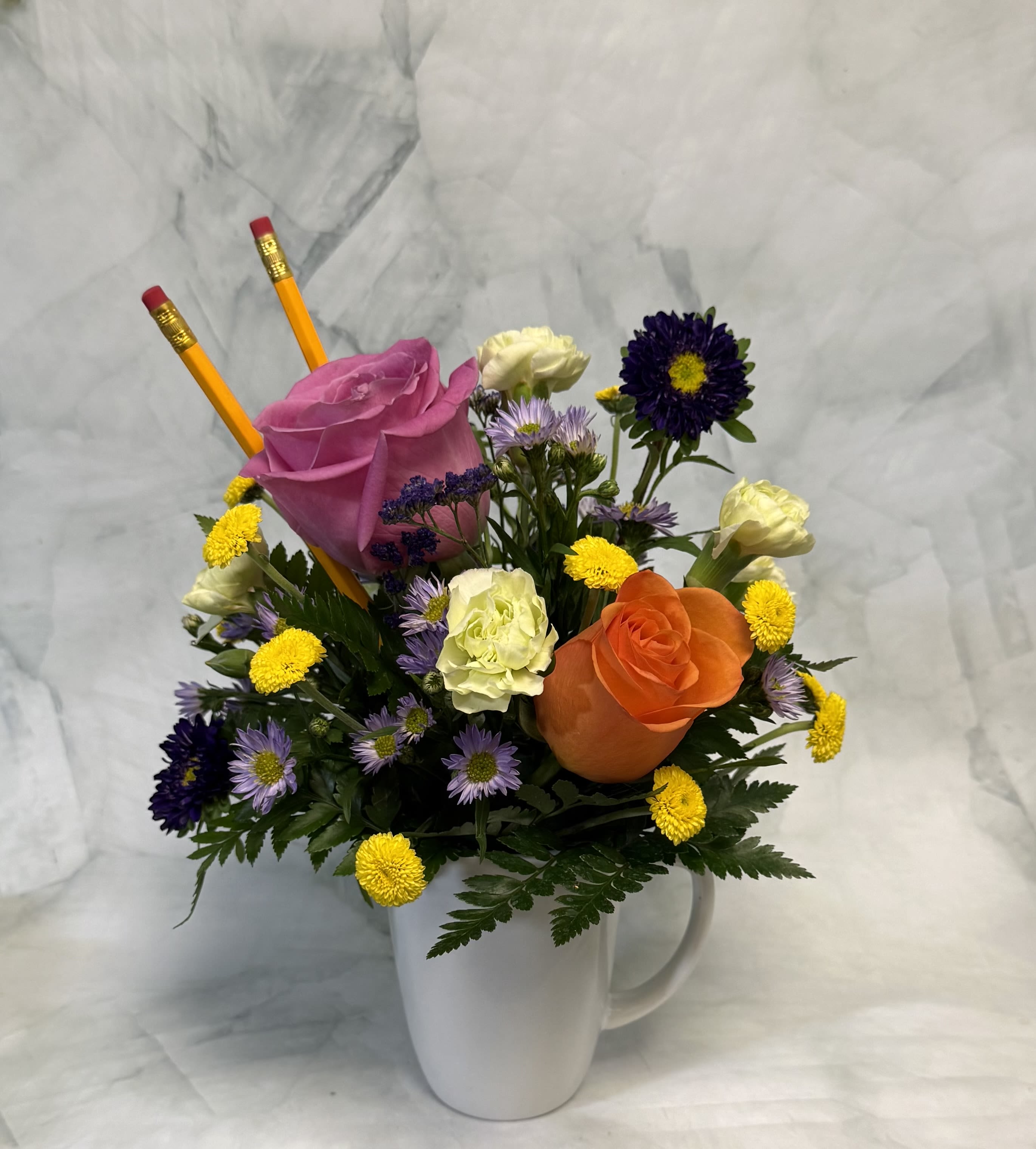 Office Appreciation Mug - Show your appreciation with this fun and thoughtful flower arrangement, perfect for celebrating your office MVP. Designed by expert florists, this unique floral gift features fresh, vibrant flowers arranged in a reusable white ceramic mug—making it both beautiful and practical. Complete with two classic pencils, this creative arrangement is ideal for office celebrations, employee appreciation gifts, and workplace flower delivery.  Perfect for sending as a thank-you gift or desk décor, this cheerful arrangement combines fresh flowers with a functional keepsake, making it a standout choice for anyone looking for unique floral gifts and office-friendly flower arrangements.