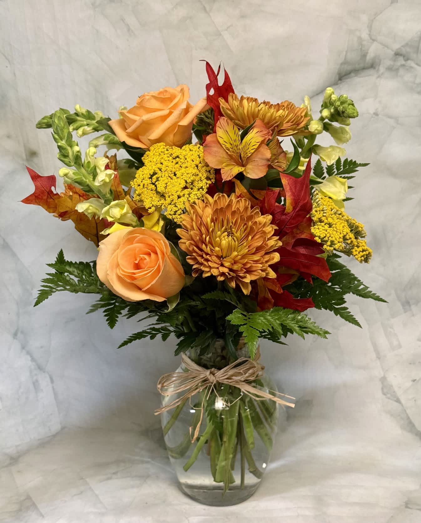 Bouquet of orange roses and yellow chrysanthemums in a glass vase