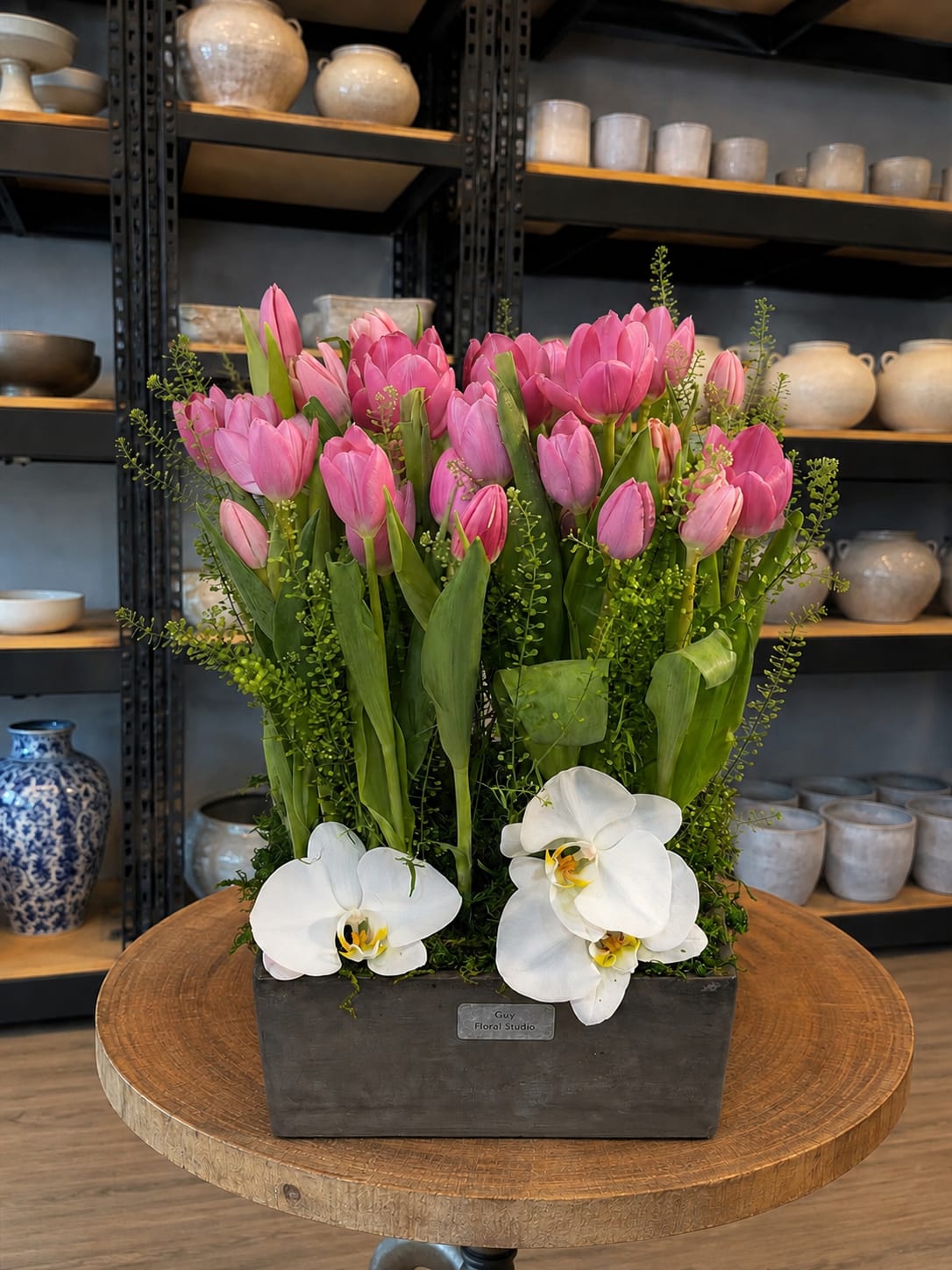 Pink tulips and white orchids arranged in a rectangular container